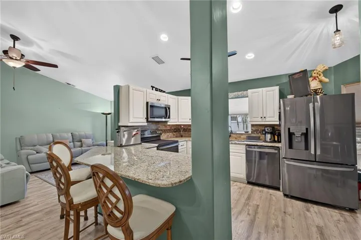 Kitchen featuring white cabinetry, stainless steel appliances, granite countertops, a built-in microwave, and wood-finish flooring