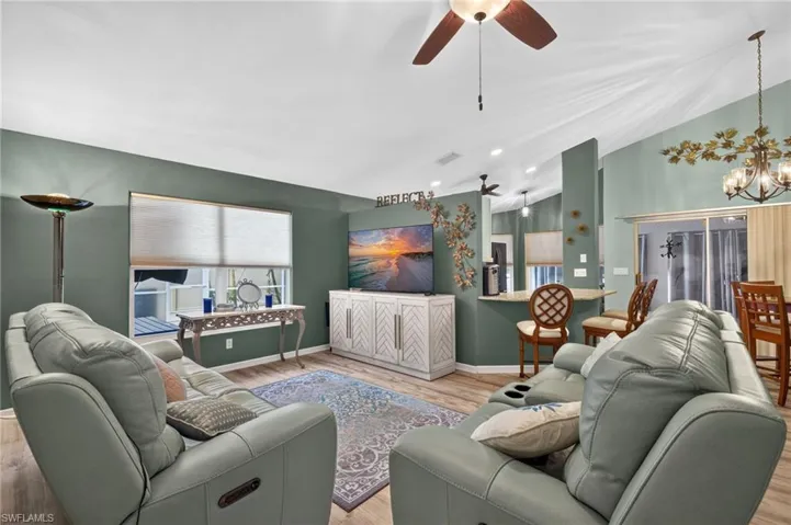 Spacious living area featuring vaulted ceilings, wood-finish flooring, recessed lighting, a ceiling fan, and a breakfast bar