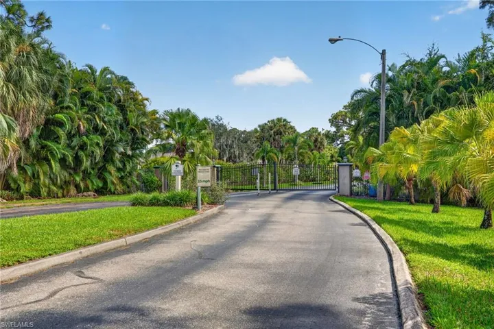 Gated entry with lush tropical landscaping and mature palm trees