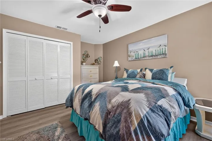 Wood-finish flooring, louvered bi-fold closet doors, and ceiling fan with integrated lighting