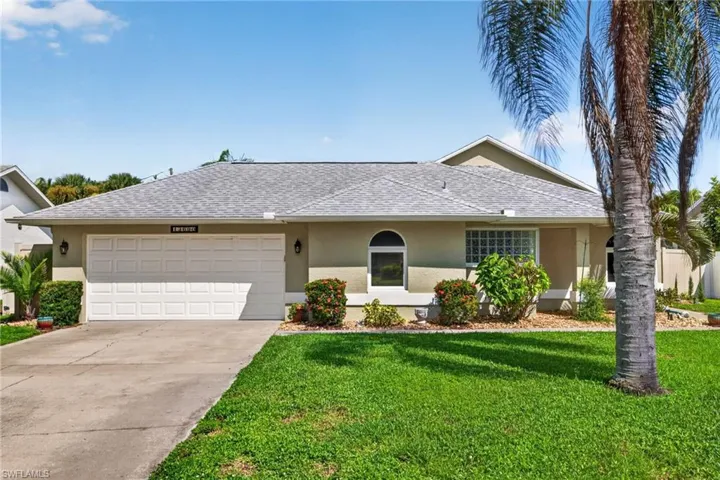 Single-story stucco exterior with a two-car garage, mature palm trees, and established landscaping