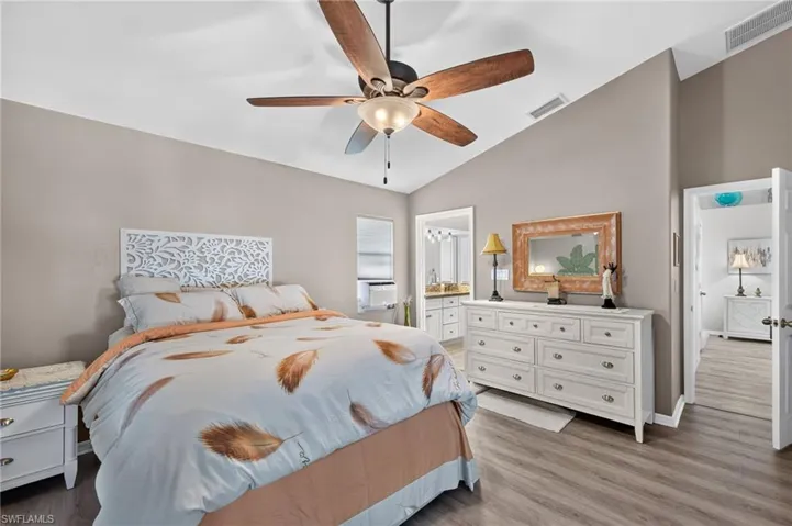 Vaulted ceiling with a ceiling fan, wood-finish flooring, and neutral wall tones