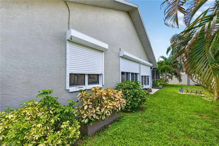 Exterior stucco finish with multiple windows featuring roll-down shutters