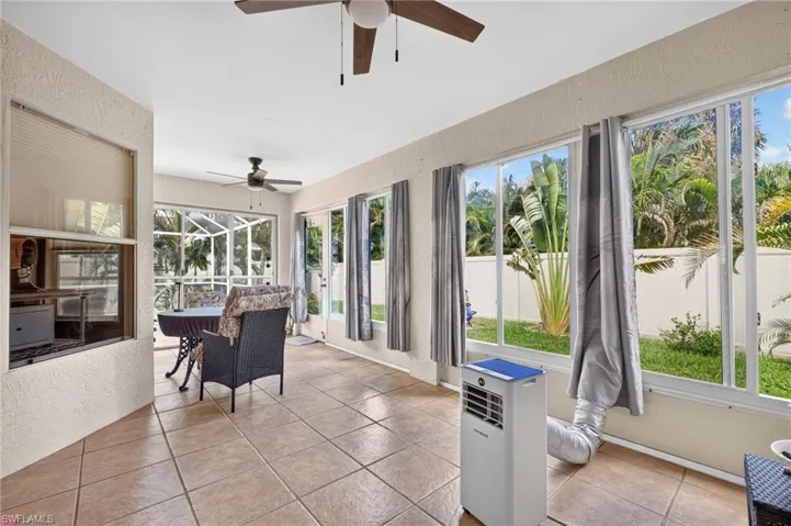 Screened patio with large format tile flooring, multiple ceiling fans, and expansive windows