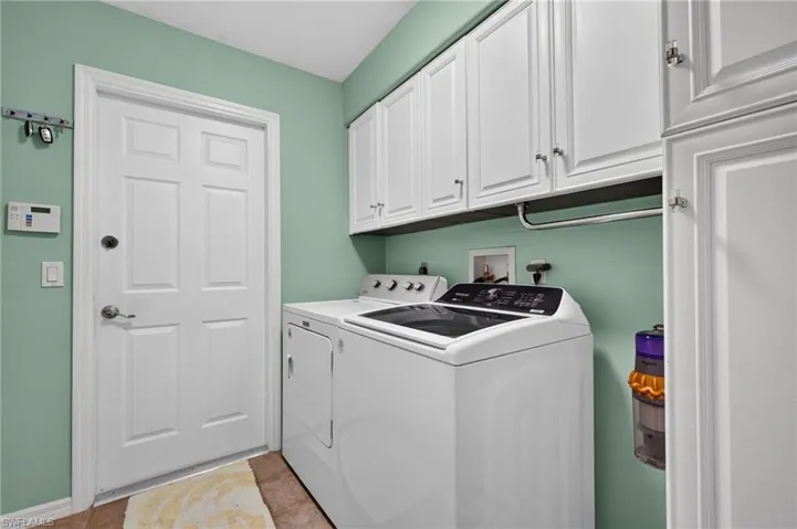 Laundry area featuring white shaker-style cabinetry, a built-in hanging rod, and tile flooring
