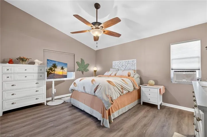 Vaulted ceiling with a ceiling fan, wood-finish flooring, and neutral wall tones