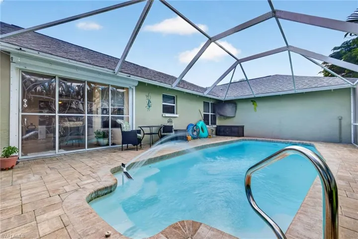 Screened swimming pool with a curved entry, paver decking, and a pool handrail