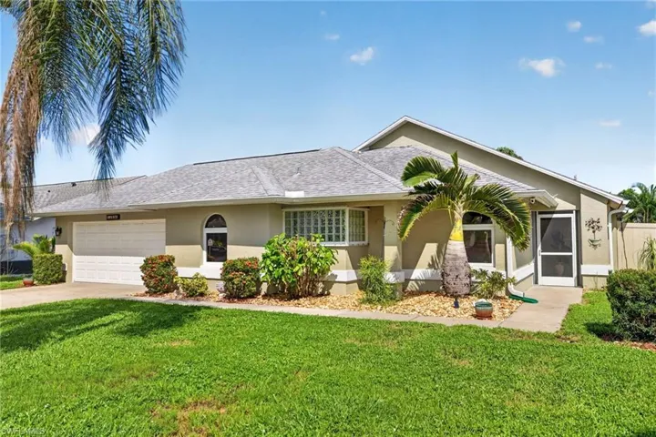 Stucco exterior with an attached garage, a screened entry, and a pitched shingle roof