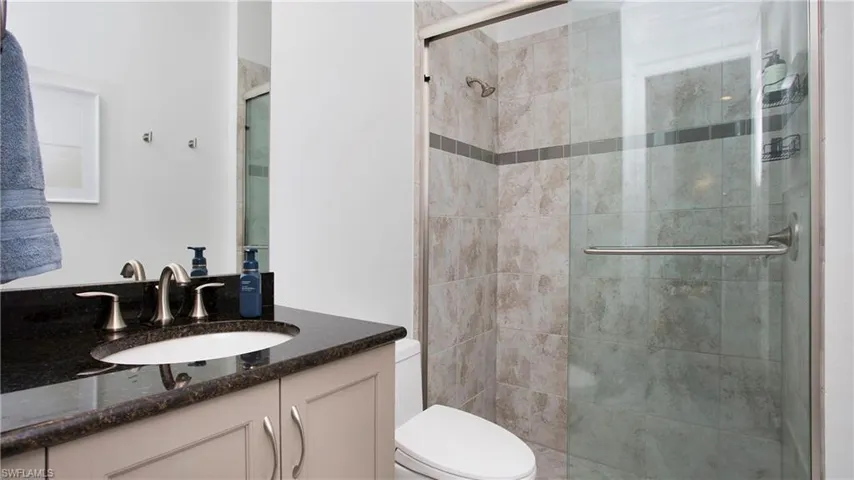 Full bath featuring a shower stall, toilet, and vanity