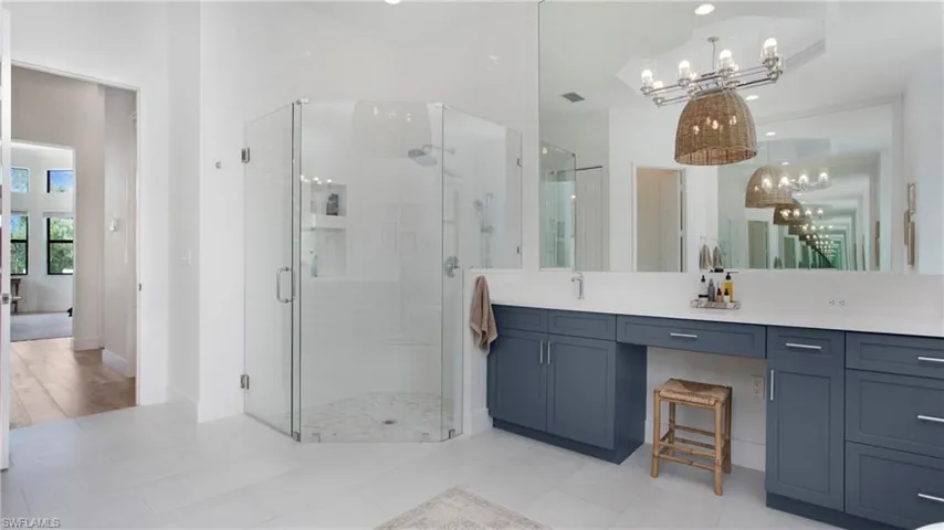 Bathroom with a chandelier, a stall shower, vanity, and baseboards