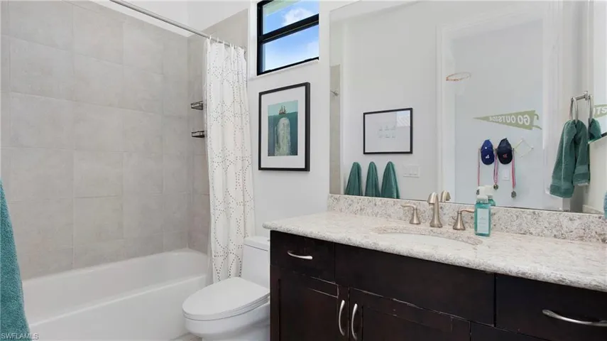 Bathroom featuring toilet, vanity, and shower / bath combo with shower curtain