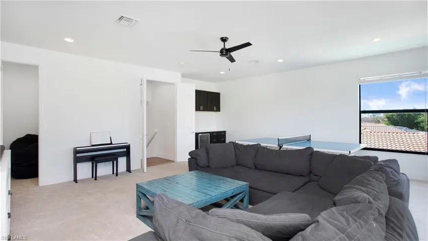 Living area with light carpet, a ceiling fan, recessed lighting, and baseboards