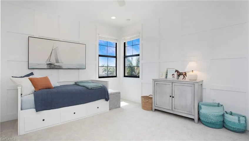 Carpeted bedroom with a decorative wall and a ceiling fan