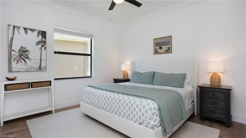 Bedroom featuring wood finished floors, crown molding, baseboards, and ceiling fan