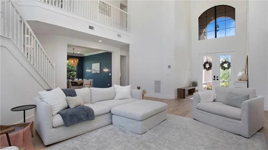Living area featuring a high ceiling, a chandelier, wood finished floors, stairway, and baseboards