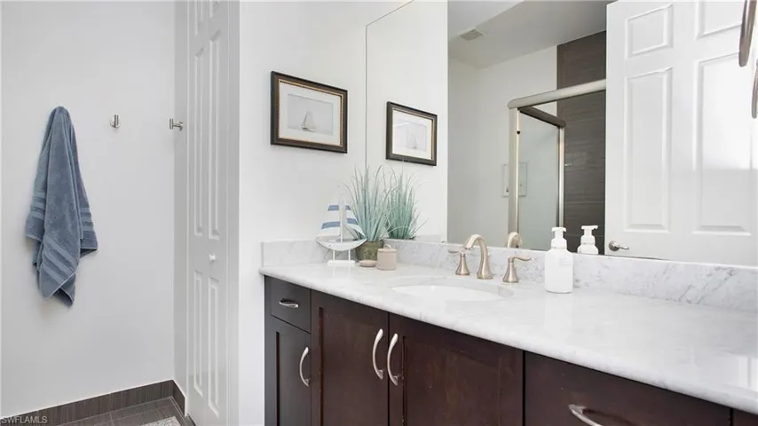 Full bath with vanity, a stall shower, tile patterned floors, and baseboards
