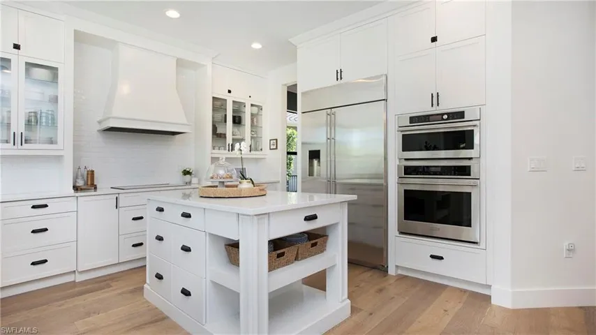 Kitchen with appliances with stainless steel finishes, custom exhaust hood, light countertops, tasteful backsplash, and recessed lighting