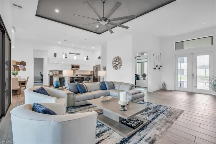 Living room with a high ceiling, french doors, light wood-type flooring, and ceiling fan