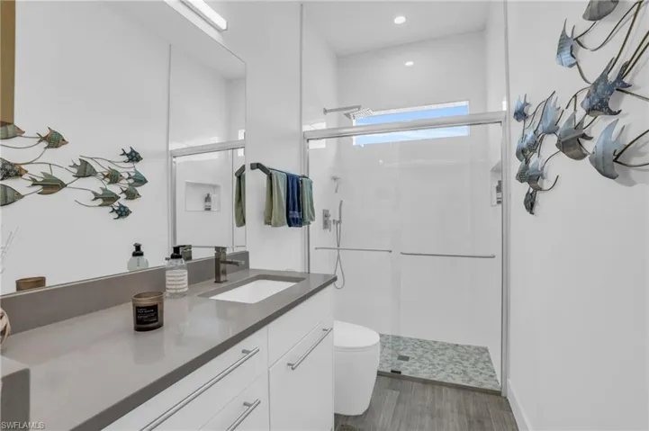 Bathroom with large vanity, toilet, and a shower with door