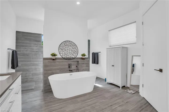 Bathroom featuring a bath, tile walls, and vanity