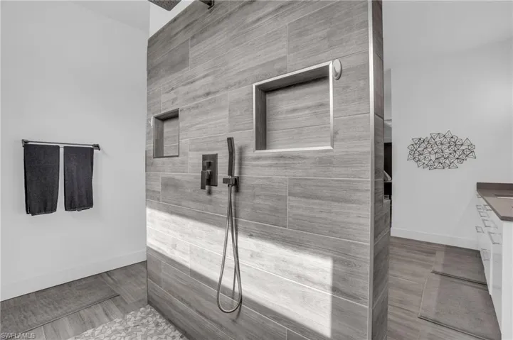 Bathroom with tile floors, tiled shower, and vanity