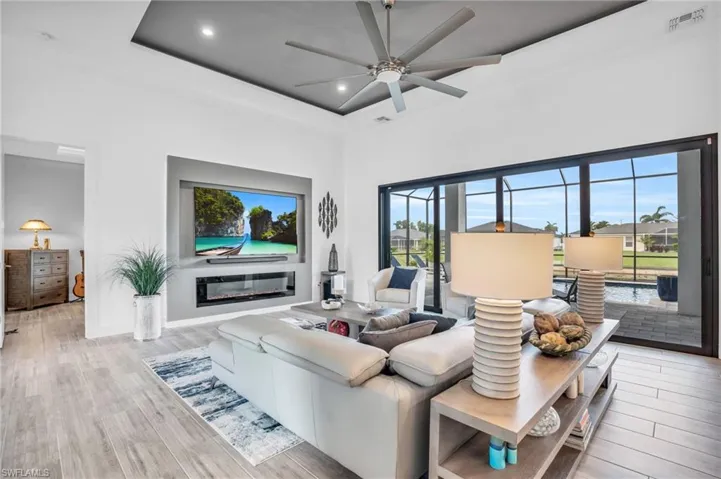 Living room with a wealth of natural light, a tray ceiling, ceiling fan, and light wood-type flooring