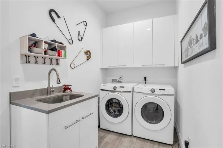 Laundry area featuring washer and dryer, cabinets, light wood-type flooring, hookup for a washing machine, and sink