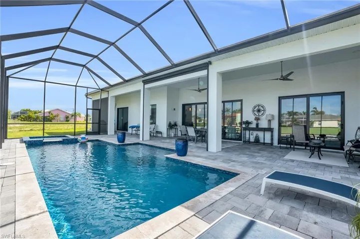 View of swimming pool featuring glass enclosure, a patio area, and ceiling fan