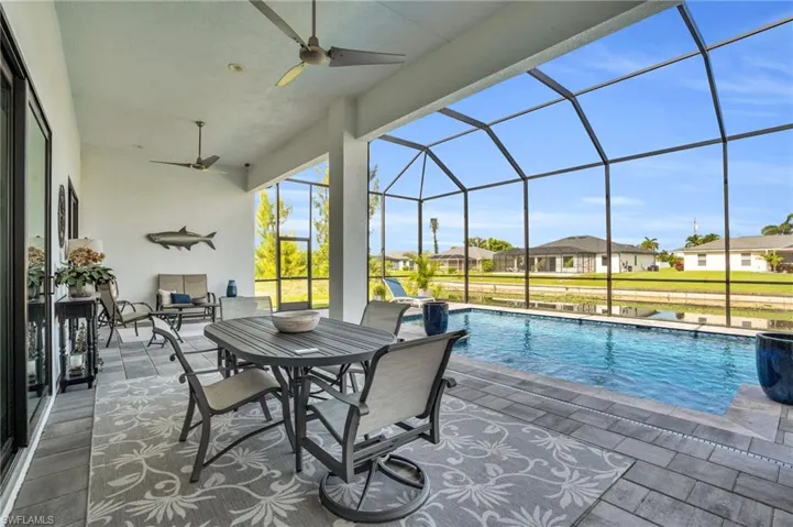 View of pool featuring a patio, glass enclosure, and ceiling fan