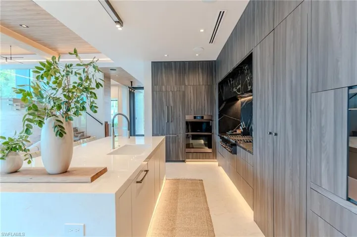 Kitchen with light stone counters, modern cabinets, appliances with stainless steel finishes, a center island with sink, and recessed lighting
