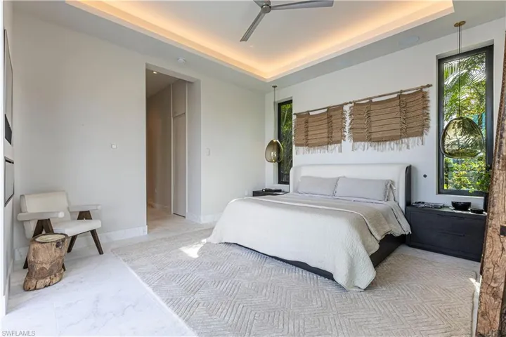 Bedroom with a raised ceilings, monolithic led cove lighting,  double windows and tasteful Italien hanging lamps
