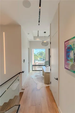 Corridor with light wood-type flooring and baseboards