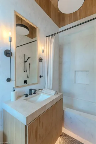 Full bathroom featuring a combined bath / shower with marble appearance and vanity