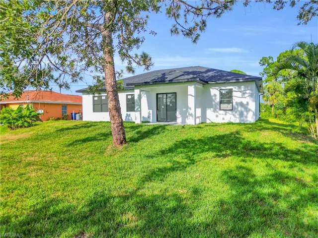 Rear view of property featuring stucco siding and a lawn