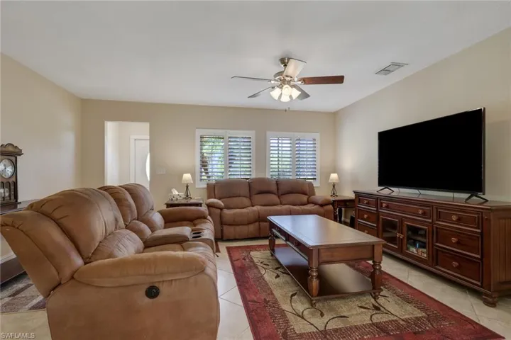 Living room with ceiling fan and light tile patterned flooring