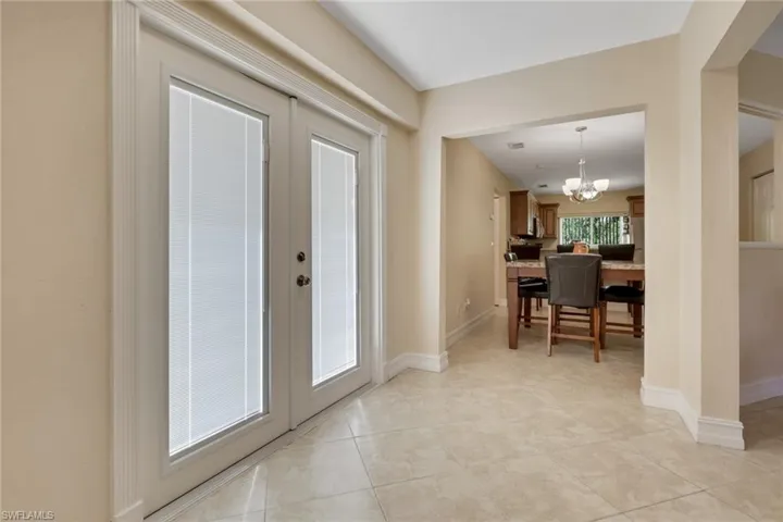 Foyer with a chandelier, french doors, and light tile patterned floors