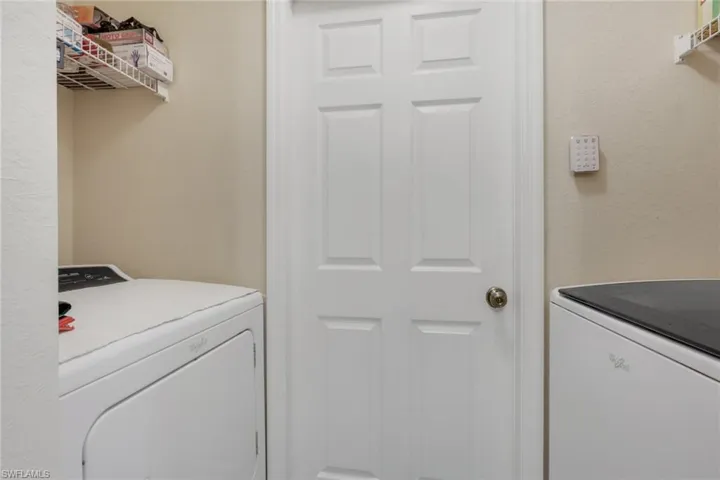 Laundry area with a textured wall and washer and clothes dryer