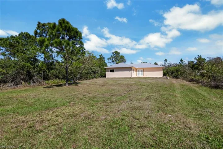 View of green lawn featuring view of wooded area