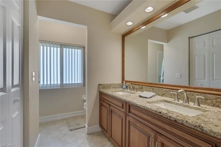 Full bathroom with double vanity, a closet, recessed lighting, and light tile patterned flooring