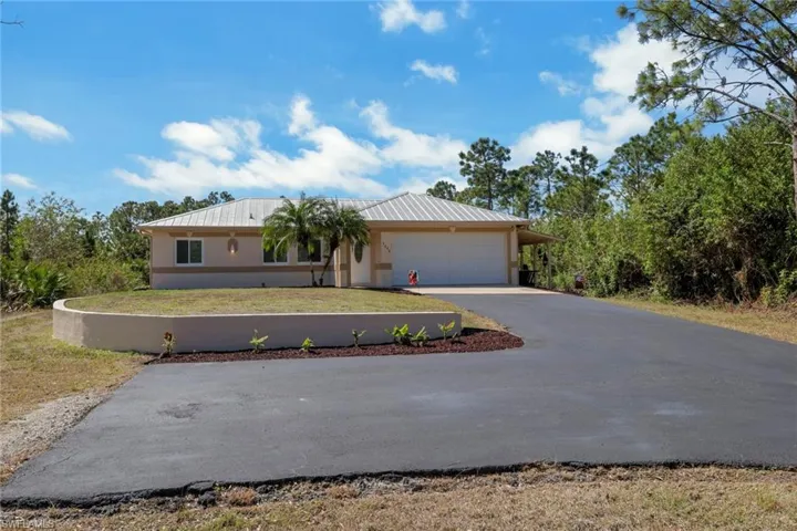 Ranch-style house with driveway, stucco siding, an attached garage, and a front yard