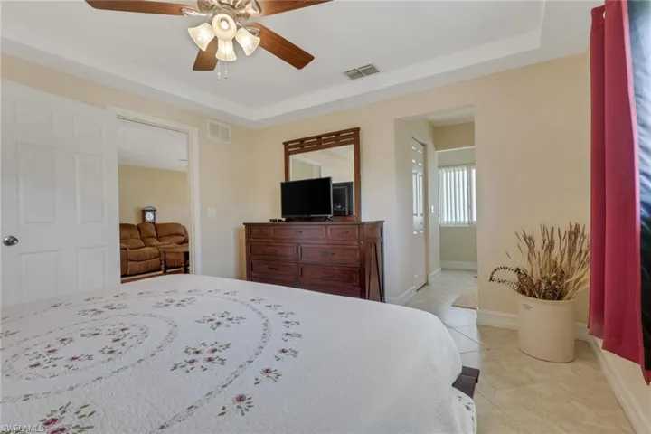 Bedroom featuring light tile patterned flooring, ceiling fan, and ensuite bath