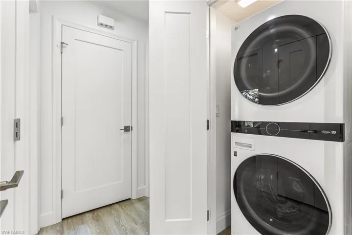 Laundry room featuring estacked washer and dryer and light wood-style floors