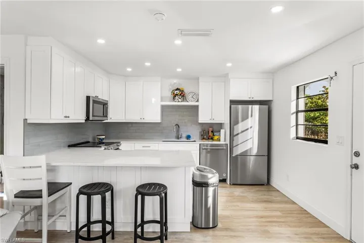 Kitchen with white cabinets, appliances with stainless steel finishes, a peninsula, a breakfast bar, and recessed lighting