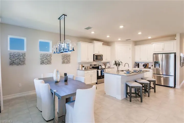 Dining area featuring light tile patterned flooring, sink, and an inviting chandelier