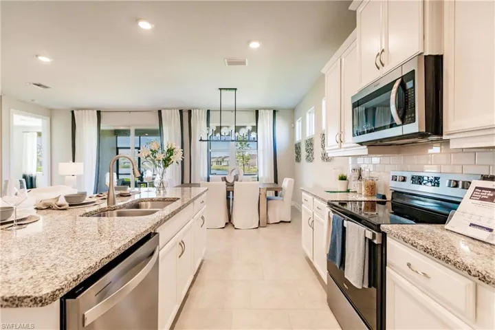 Kitchen featuring light tile patterned floors, stainless steel appliances, decorative backsplash, pendant lighting, and sink