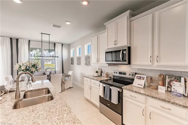 Kitchen with hanging light fixtures, appliances with stainless steel finishes, tasteful backsplash, and sink