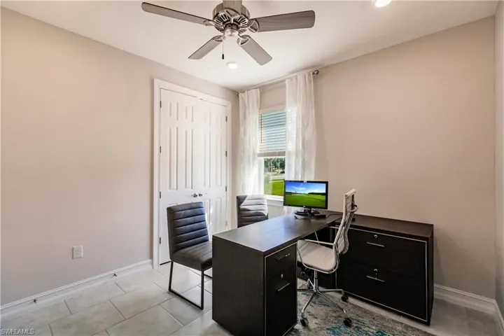 Home office with light tile patterned floors and ceiling fan
