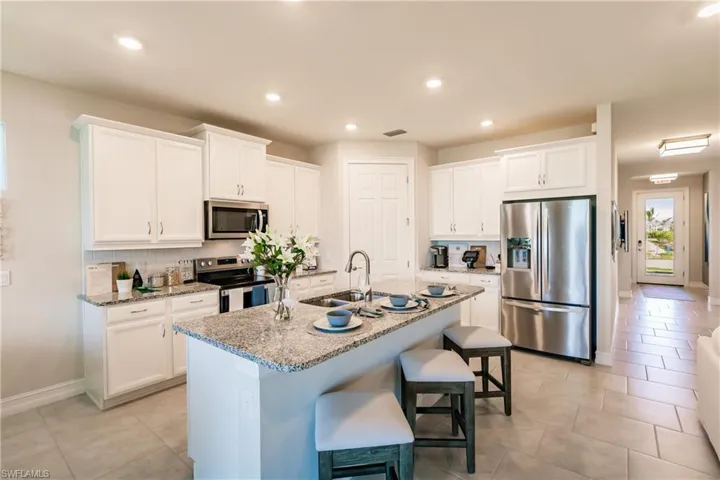 Kitchen featuring sink, backsplash, a center island with sink, and stainless steel appliances