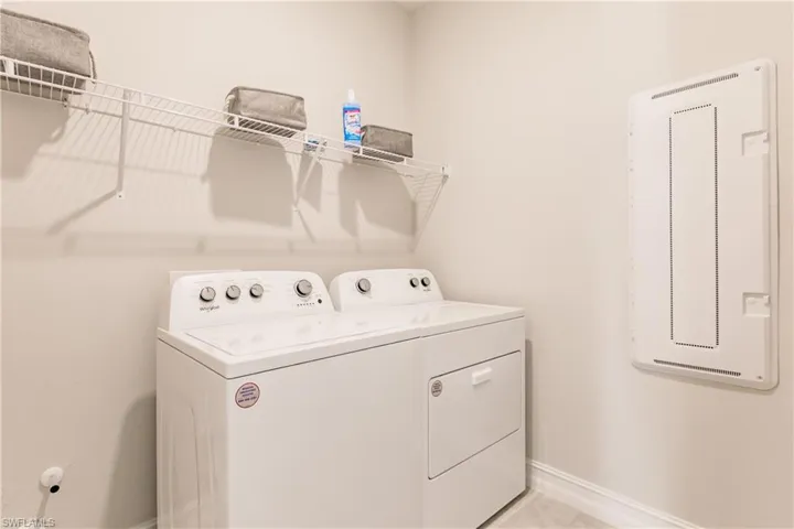 Laundry room with washing machine and clothes dryer and light tile patterned floors
