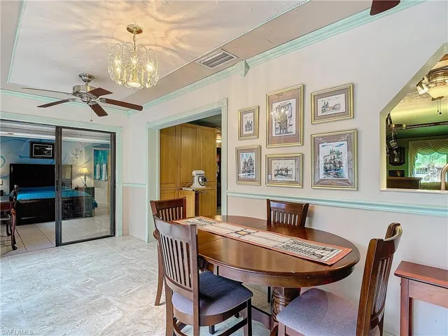 Tiled dining area with ceiling fan with notable chandelier